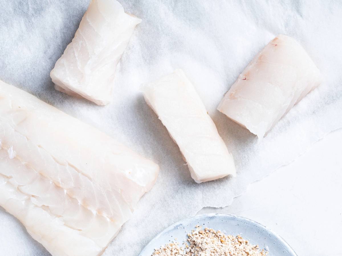 Fiskepinner ligger på et hvitt underlag, klare til å bli stekt eller bakt.