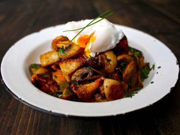 Soppesalat med sopp, urter og en klatt rømme på en hvit tallerken.