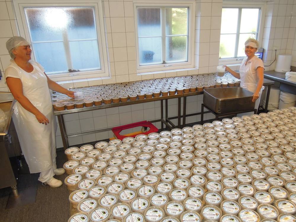 To personer står i et rom med mange ferdigpakkede matbokser på bord og gulv, klare til distribusjon.