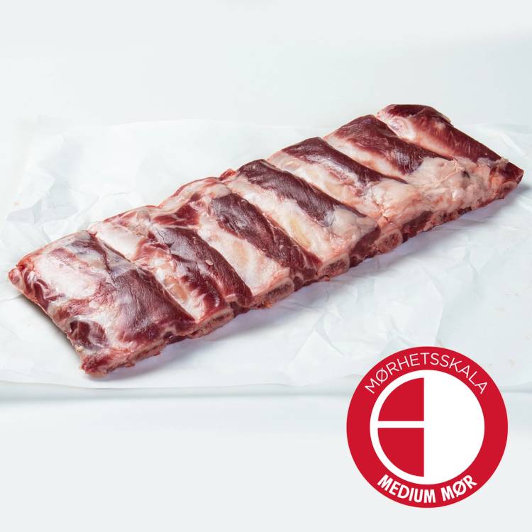 Angus short ribs pakket med ben, merket med Mørhetsskala Medium Mør, liggende på hvit bakgrunn.