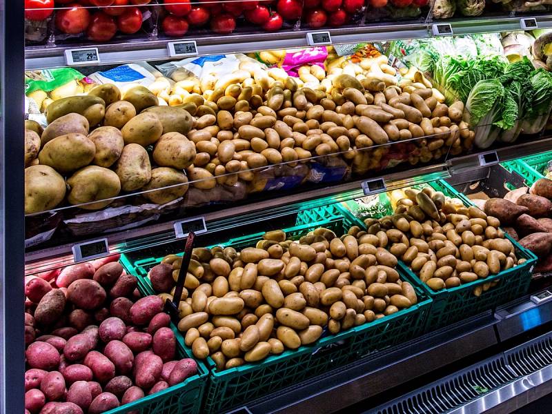 Ferske poteter og rotgrønnsaker i en grønnsaksdisk i en butikk, med ulike varianter og farger.