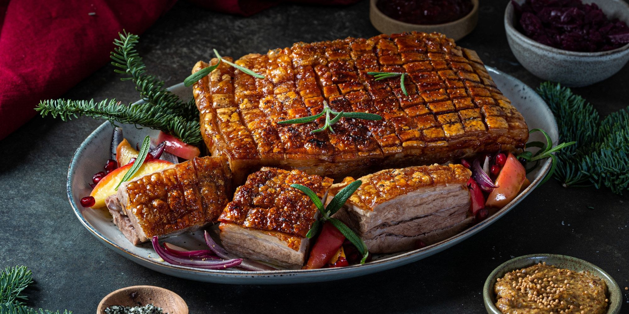 Ribbe med sprø svor, servert med grønnsaker og julepynt, på et fat.