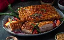 Ribbe med sprø svor, servert med grønnsaker og julepynt, på et fat.