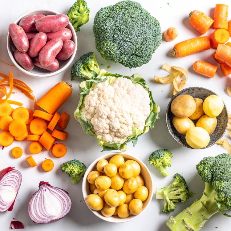 Ulike ferske grønnsaker som brokkoli, blomkål, gulrøtter, rødløk, poteter og kål på en hvit bakgrunn