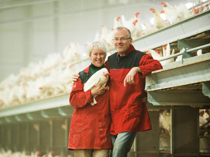 Joar og Ingrid står i en hønsegård med høner rundt seg, og Ingrid holder en høne i armene.