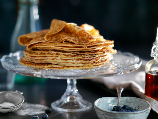Pannekaker stablet oppå hverandre på et glassfat, klare for servering.