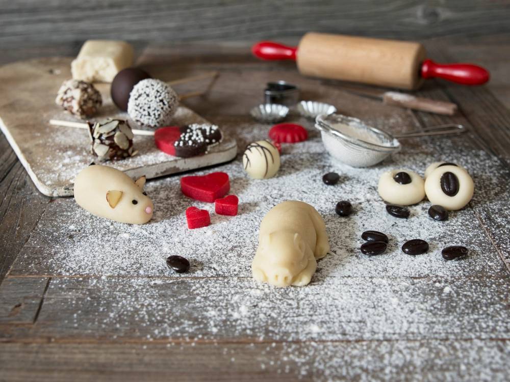 Hjemmelaget marispan og småkaker på et kjøkkenbord med kjevle og mel i bakgrunnen.