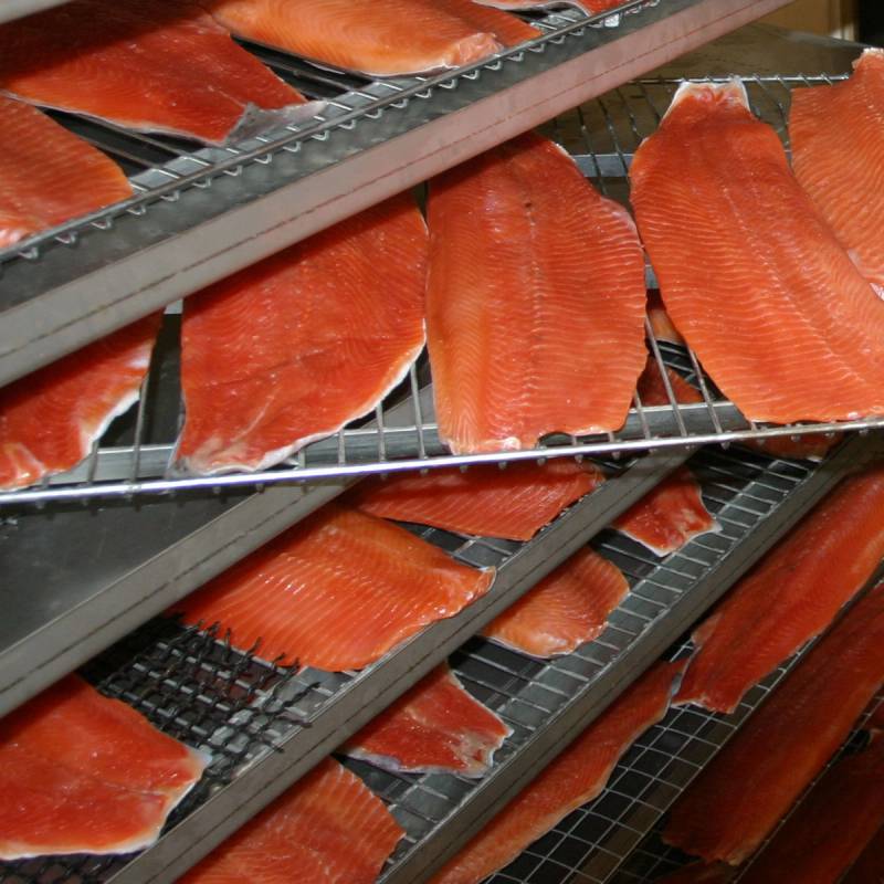 Laksestykker tørkes på rister i en lakseproduksjonsfasilitet.