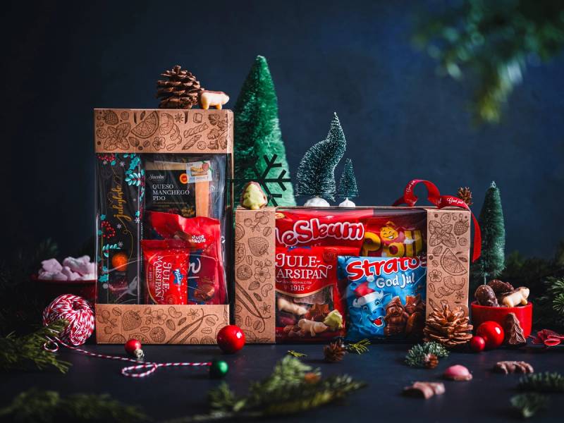 Julegaver i esker med julepynt og små dekorasjoner rundt, satt opp mot en mørk bakgrunn.