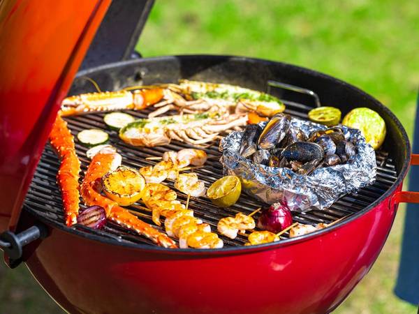 Grill med skalldyr og grønnsaker som er i ferd med å bli grillet på en kullgrill utendørs.