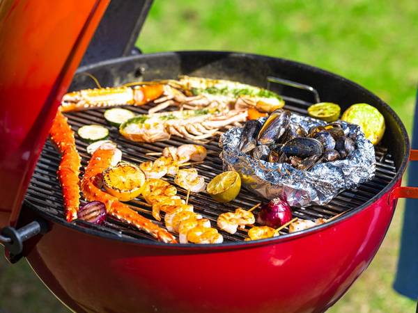 Grill med skalldyr og grønnsaker som er i ferd med å bli grillet på en kullgrill utendørs.