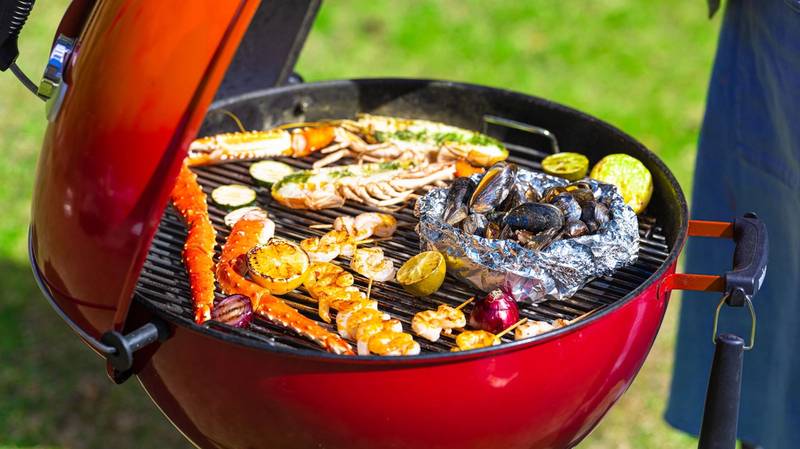 Grill med skalldyr og grønnsaker som er i ferd med å bli grillet på en kullgrill utendørs.