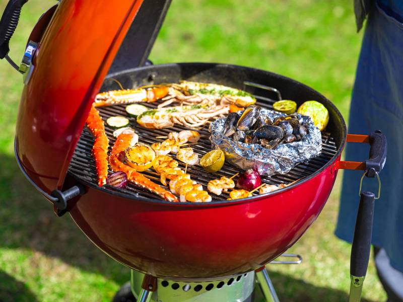 Grill med skalldyr og grønnsaker som er i ferd med å bli grillet på en kullgrill utendørs.