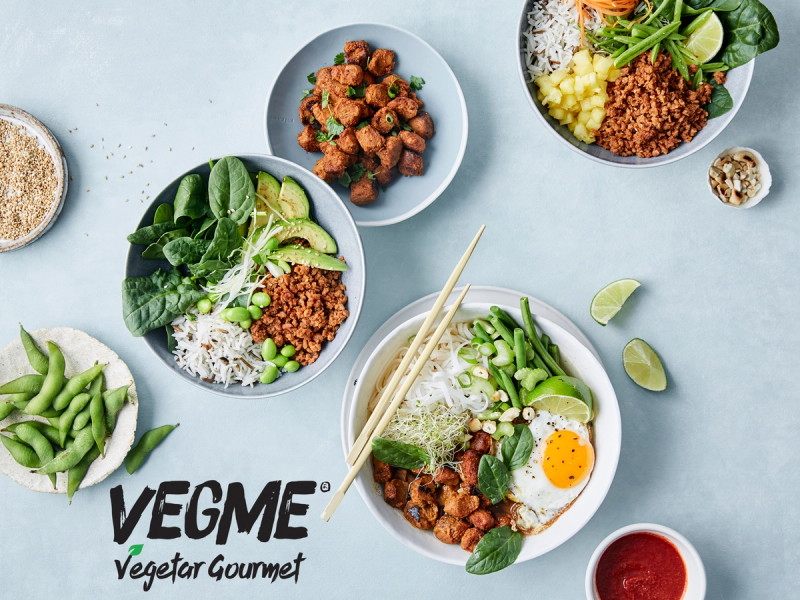 En tallerken med ris, grønnsaker og kjøttdeig, omgitt av flere små skåler med ulike ingredienser, på en lys bakgrunn.