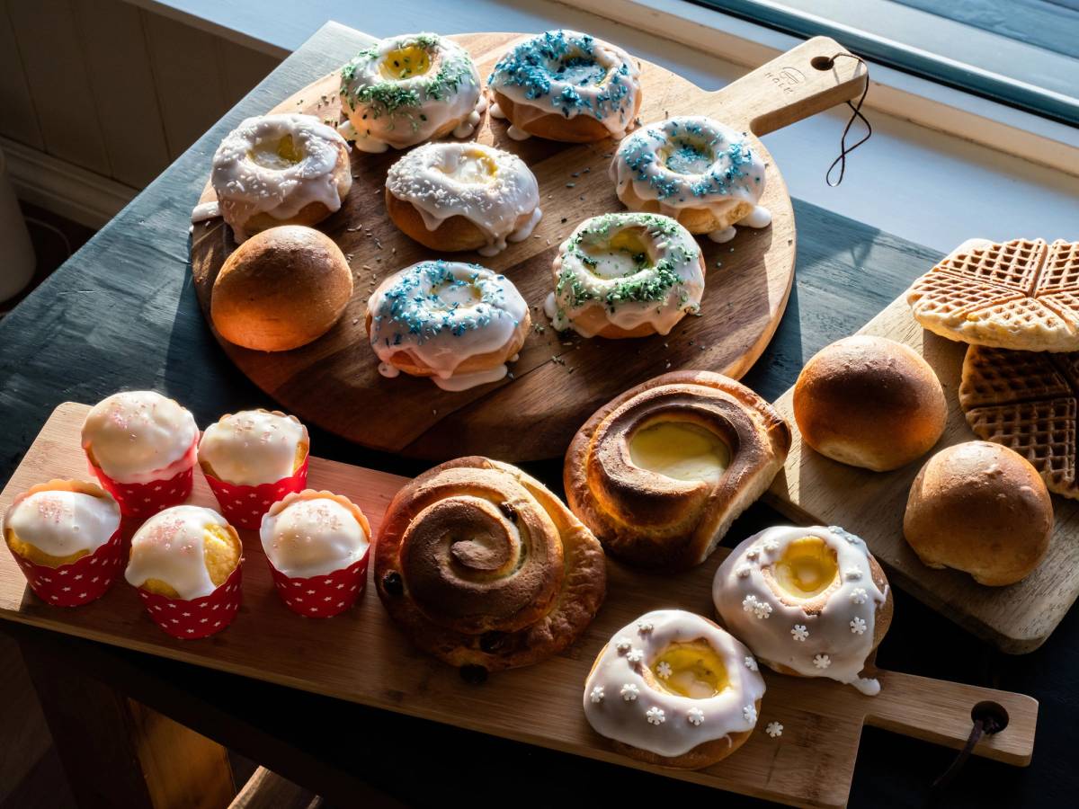 Ulike typer kaker og bakverk på et bord, inkludert donuts med glasur og strøssel, samt små kaker i papirformer.