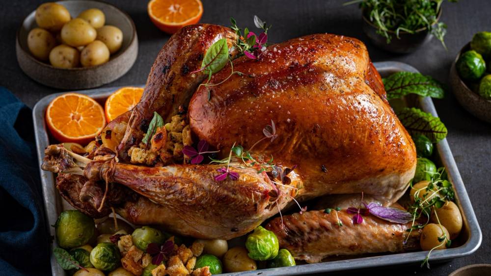 Stekt kalkun med grønnsaker og sitrusfrukter rundt på et fat, klar til servering.