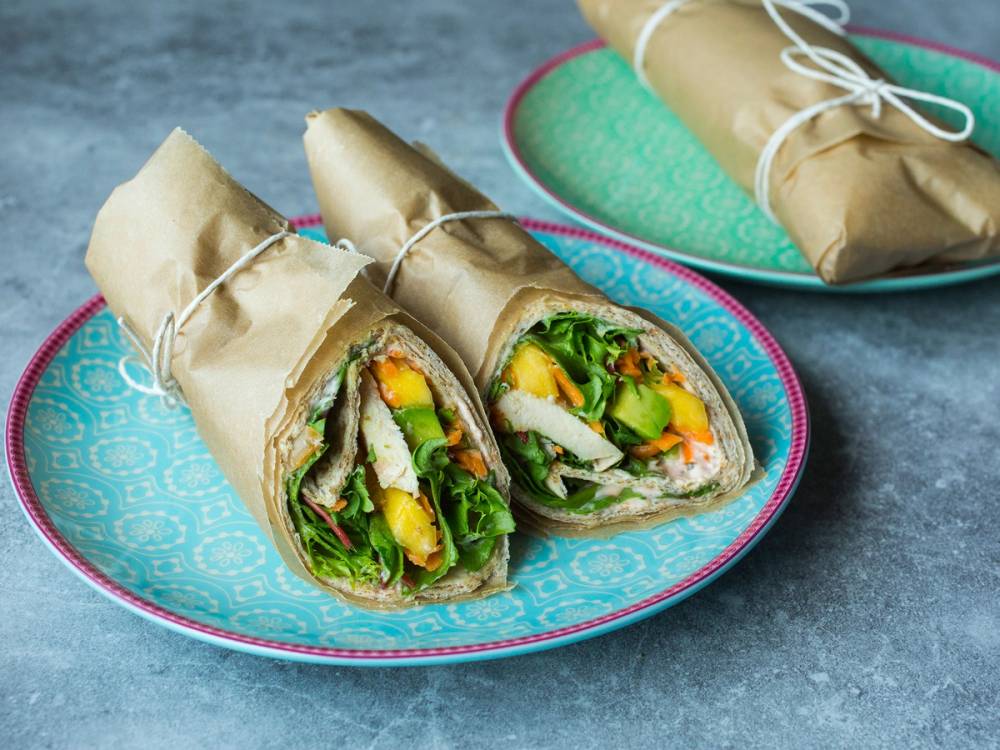 Grove wraps med mango og kylling på en blå tallerken, med flere wraps i bakgrunnen.