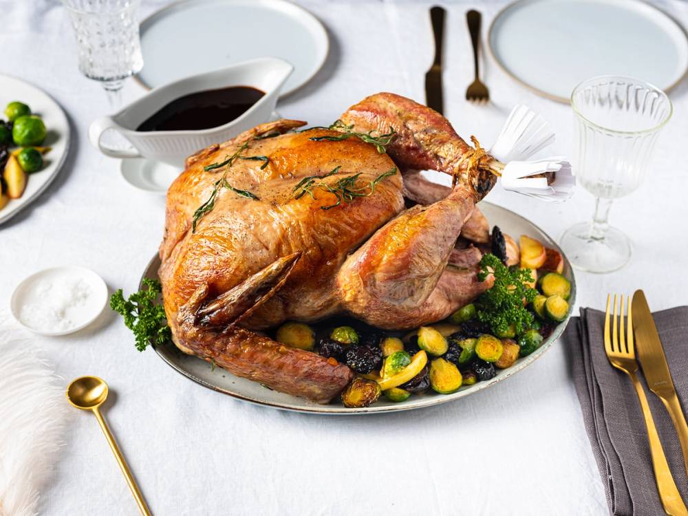 Stekt kalkun med grønnsaker og urter på et festmåltid med hvit bakgrunn.