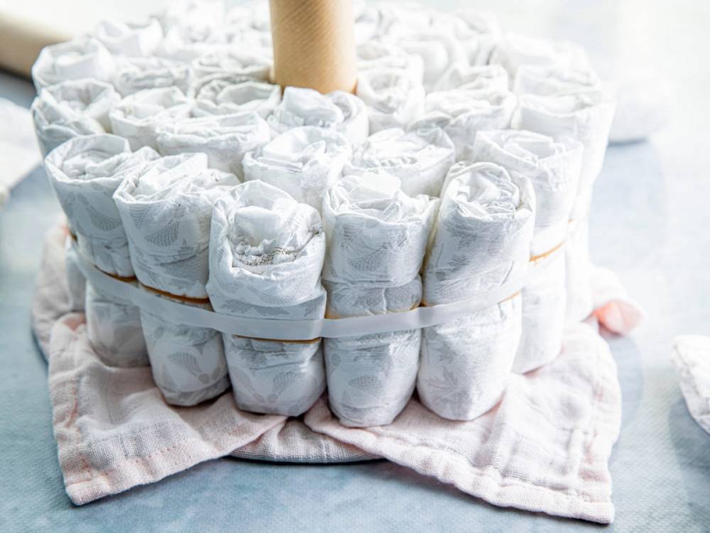 En bleiekake laget av flere sammenrullede bleier stablet i en sirkel på et hvitt underlag.