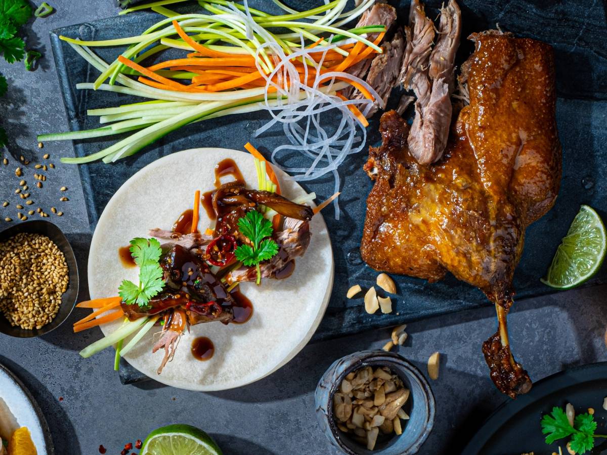 Asiatisk inspirert rett med sprø svineknoke, friske grønnsaker og lime på en mørk bakgrunn.