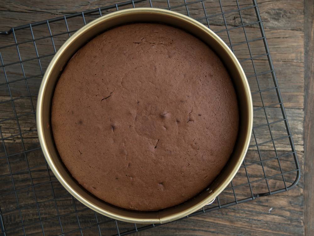 En rund sommerfuglkake som er ferdig stekt og avkjølt i en rund form på en avkjølingsrist.