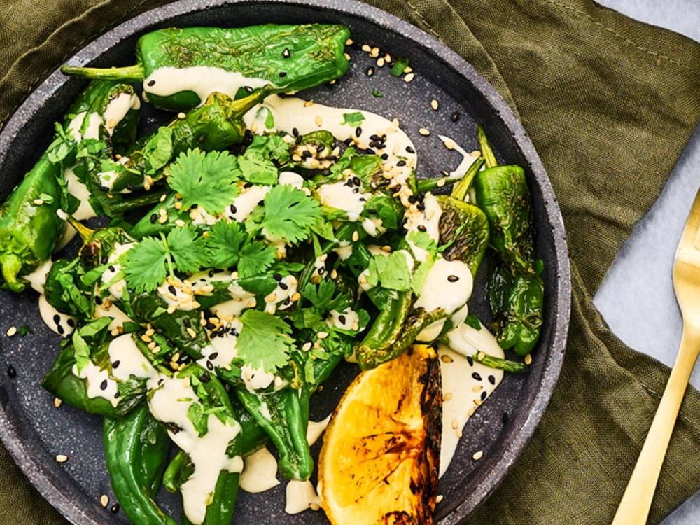 Grønnsaker som paprika, løk og chili i en stekepanne med frisk koriander på toppen.