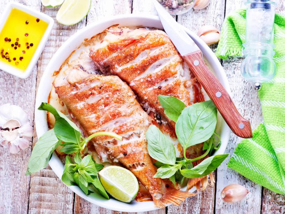 Grillet fiskestykke med sitronbåter og friske urter på en tallerken