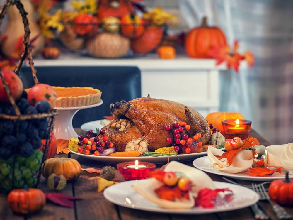 En Thanksgiving-middag med kalkun på et bord pyntet med høstblomster og lys.