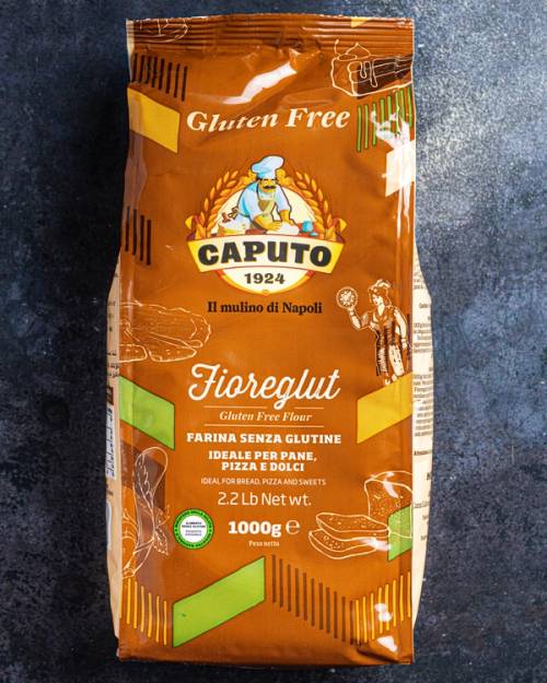 Pakke med glutenfritt pizzamel fra merket Caputo, fargen er hovedsakelig brun med gul og grønn dekorasjon.