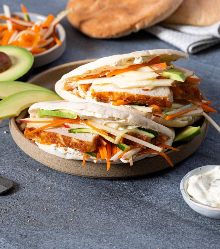 Fiskekaker i pita med grønnsaker og dressing på en tallerken.