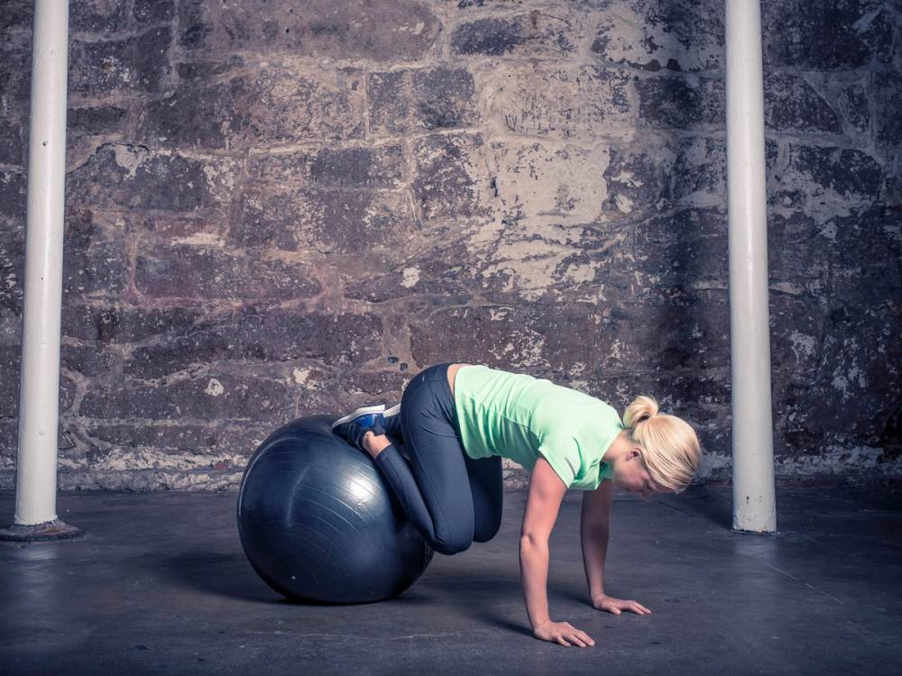 En person som trener med en stor treningsball i et treningsrom.