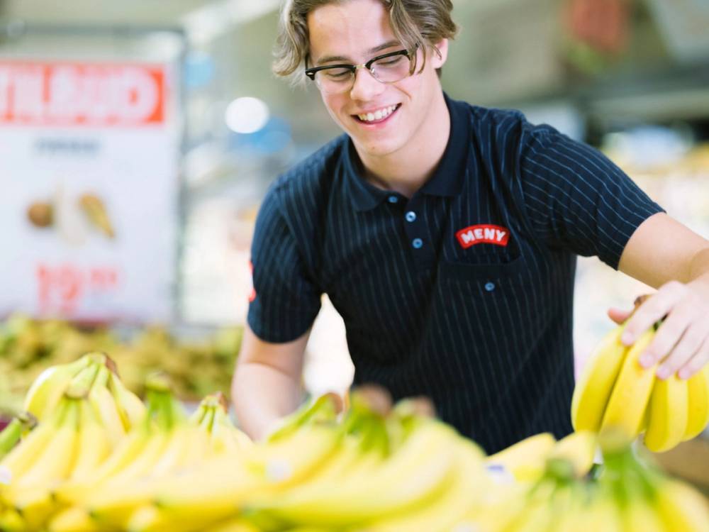 En person med blurrert ansikt plukker bananer i en butikk eller på markedet.