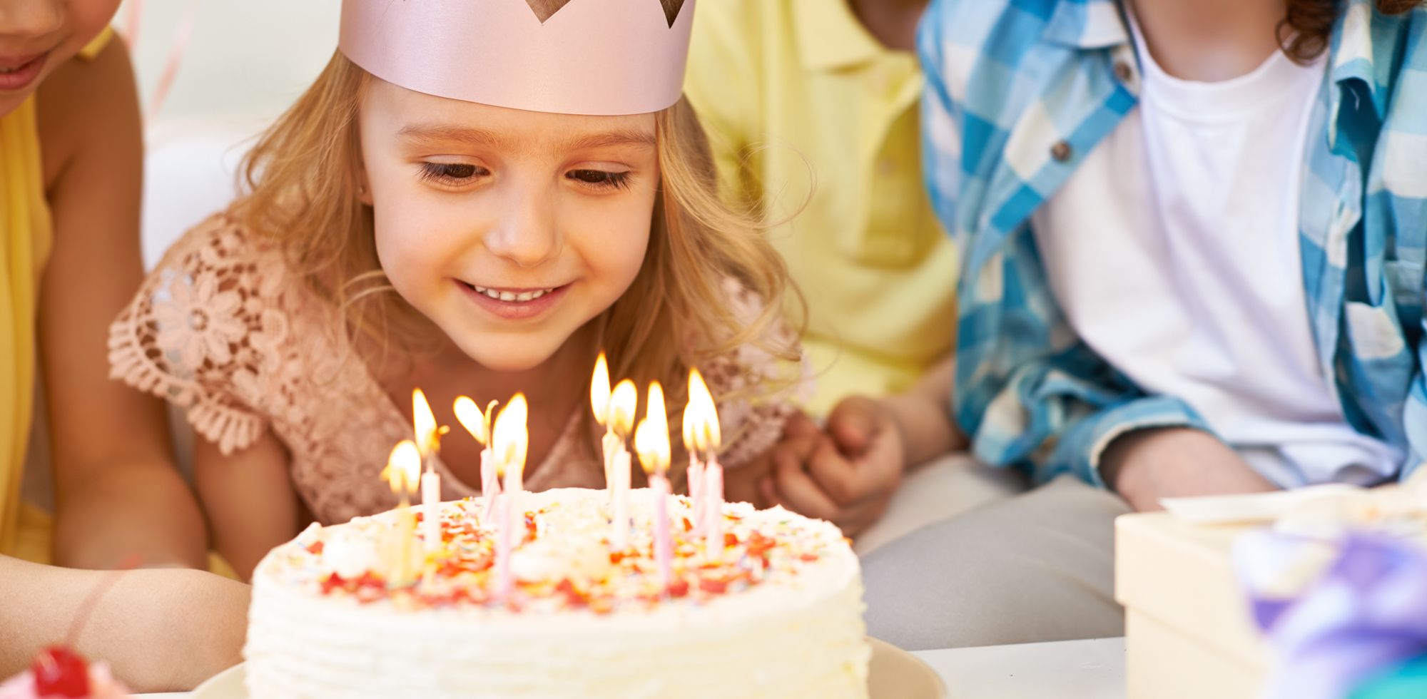 Barn feirer bursdag med en kake med lys, omgitt av venner eller familie.