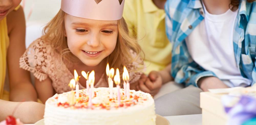 Barn feirer bursdag med en kake med lys, omgitt av venner eller familie.