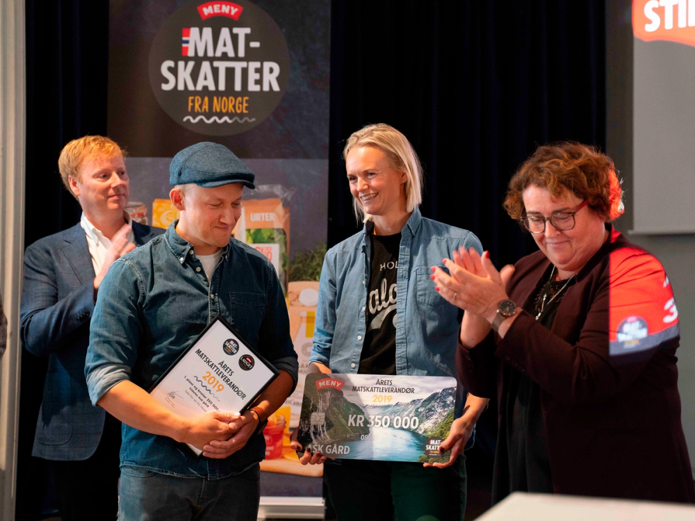 En gruppe personer mottar en sjekk under en seremoni for Matskattstipendet 2019, med en plakat i bakgrunnen som viser stipendets navn.