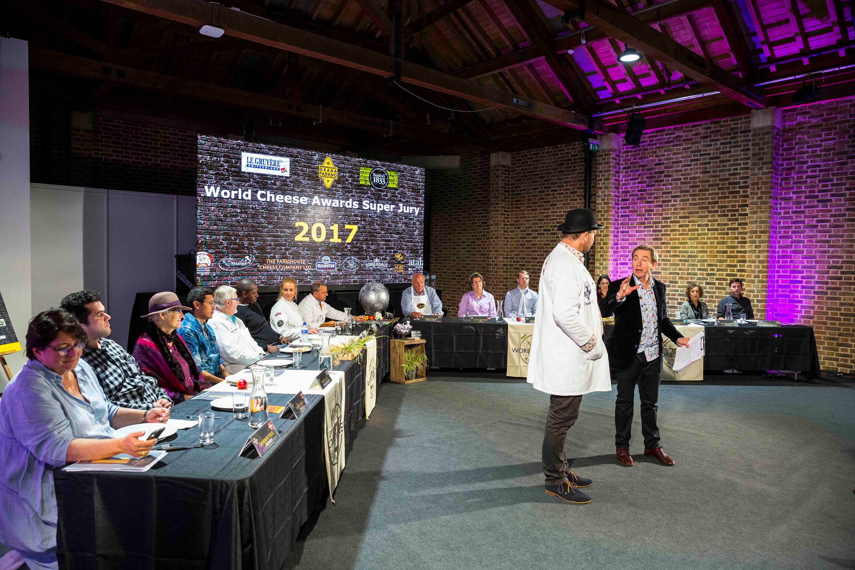 Personer deltar i en konferanse med en stor skjerm som viser 'World Chess Championship 2017' i bakgrunnen.