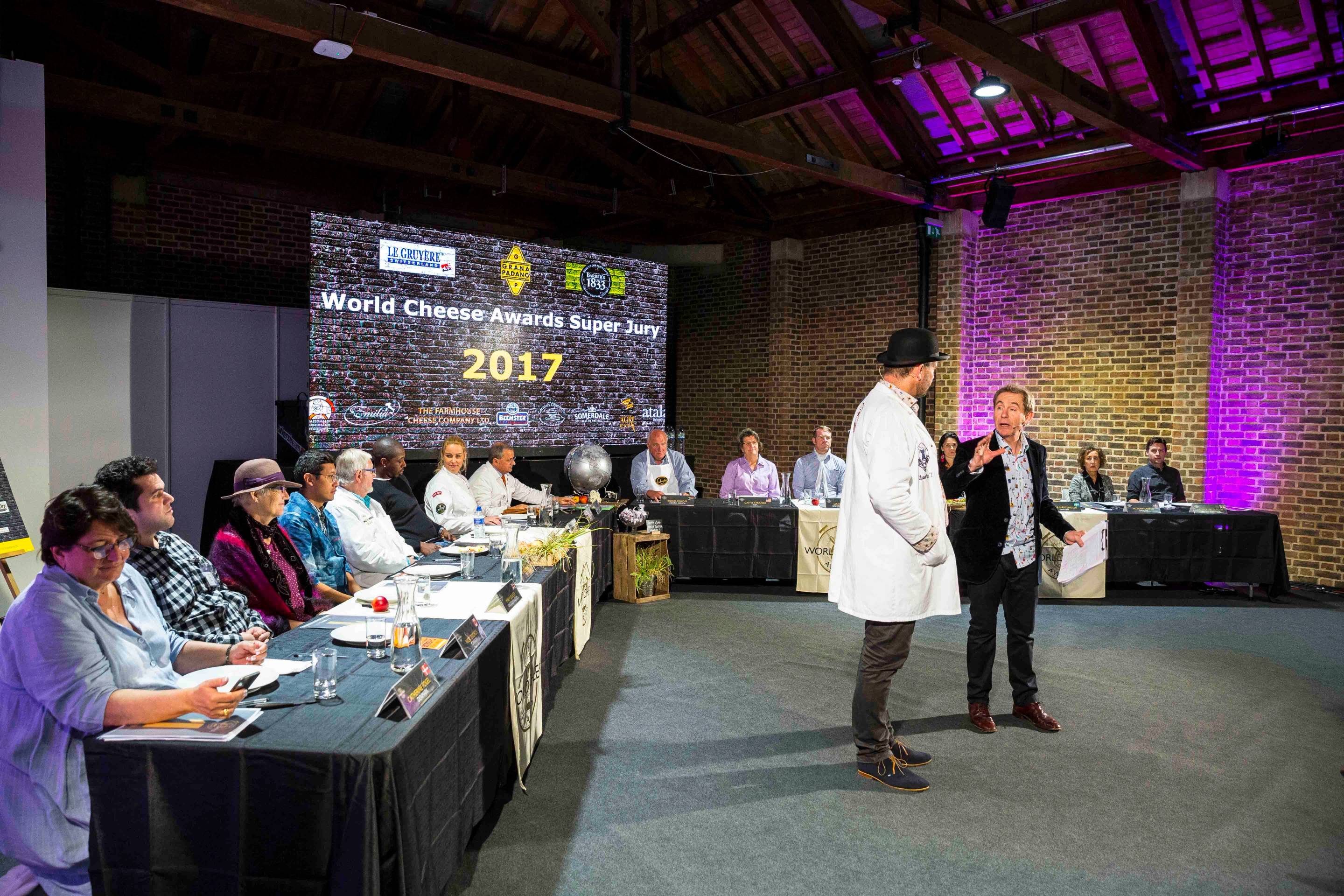 Personer deltar i en konferanse med en stor skjerm som viser 'World Chess Championship 2017' i bakgrunnen.