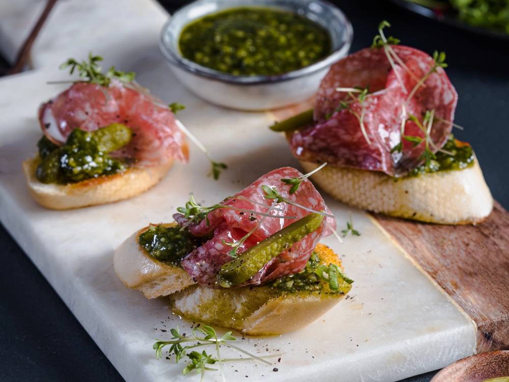 Bruschetta med skinke, grønn pesto og urter på et fat
