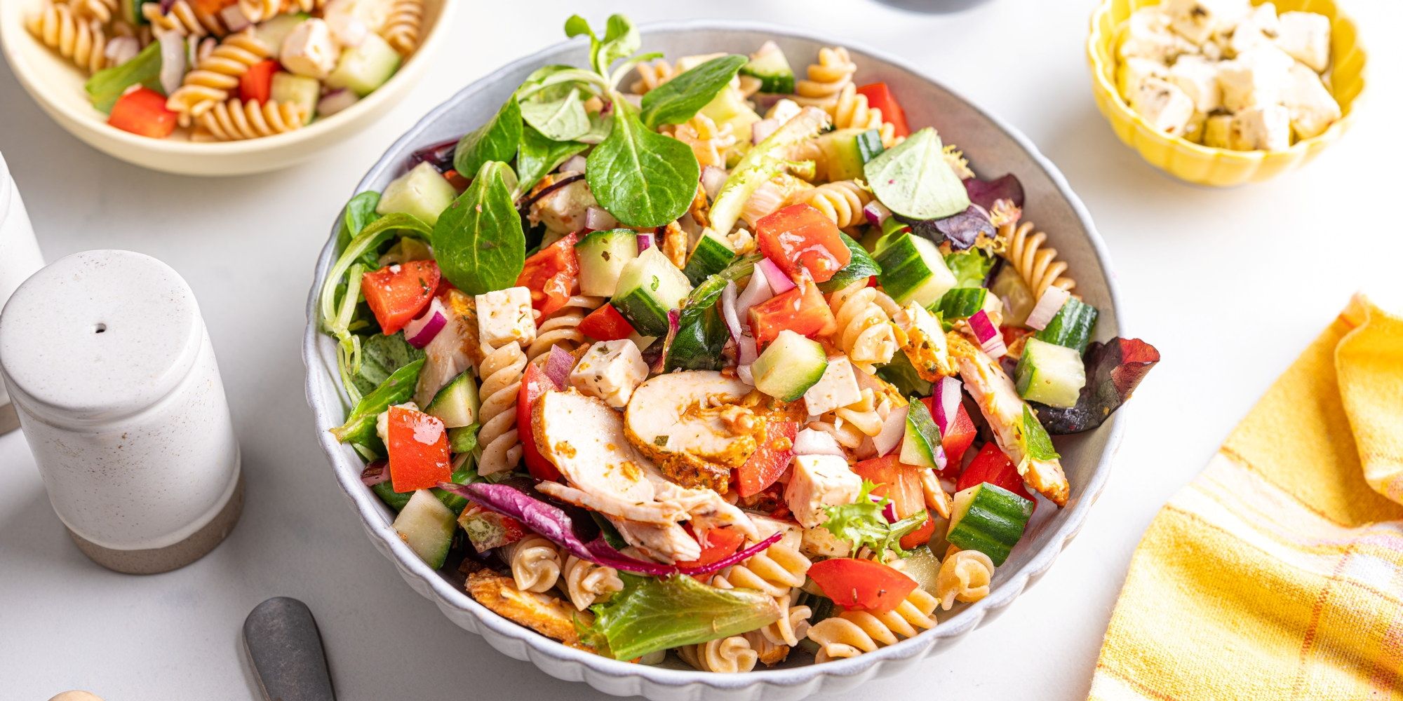 Fargerik pastasalat med fusilli, kyllingbiter, cherrytomater, agurk og salat i en stor bolle.