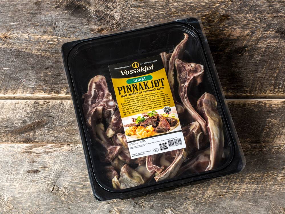 Pakke med pinnekjøtt med ribbeinsstykker i en svart plastboks, klar til tilberedning.