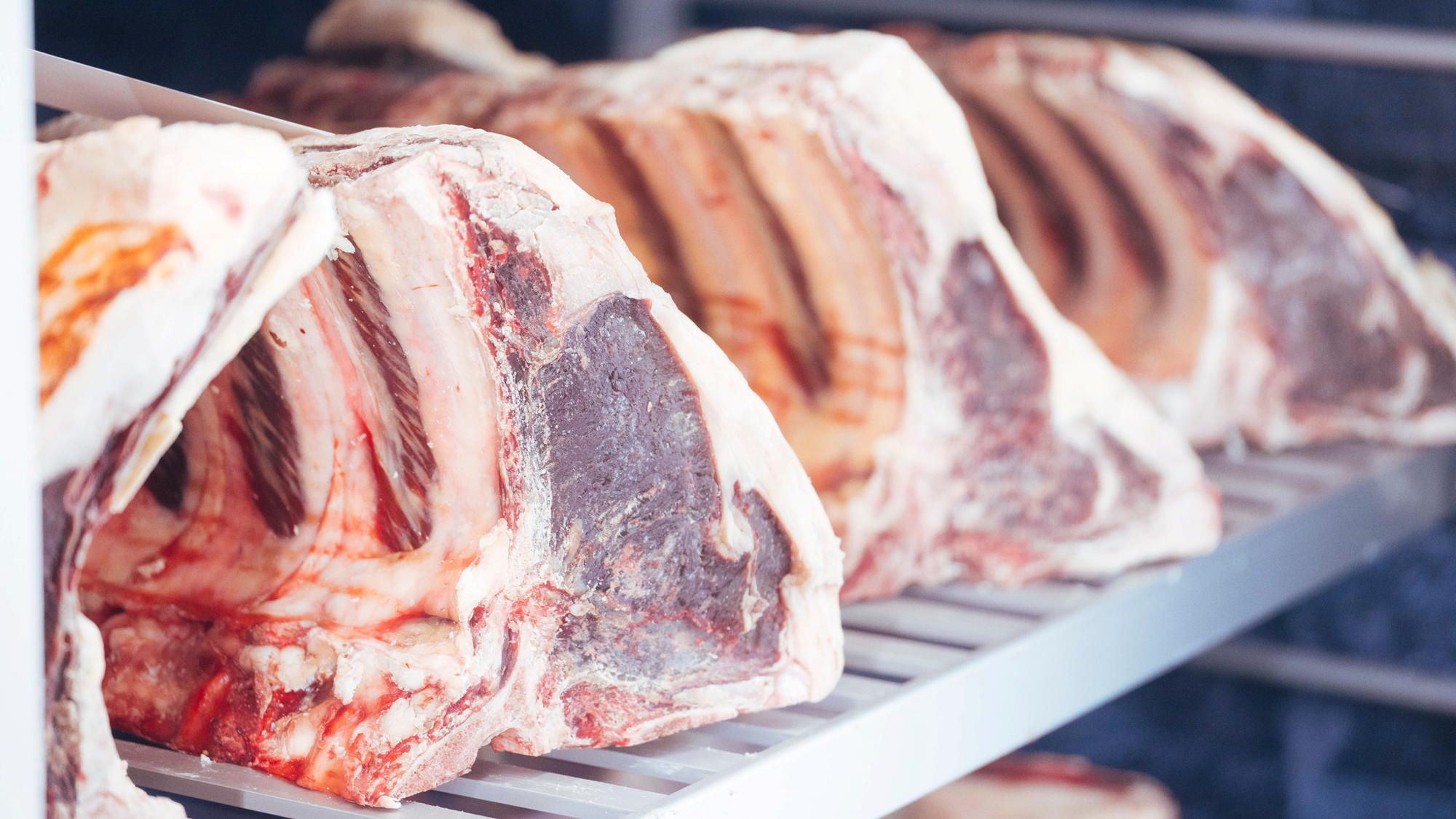 Kjøttstykker som ligger til tørk i et modningsskap.