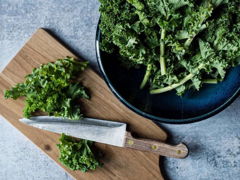 Fersk grønnkål på en skjærefjøl og i en bolle, klar til å bli brukt i matlaging.