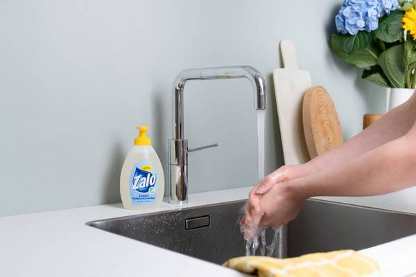 Hender som vasker seg med Zalo håndsåpe under en kjøkkenkran.