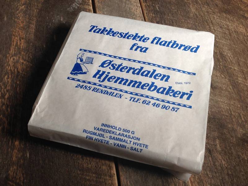 En pakke med takketeste flatbrød fra Østerdalen Hjemmebakeri ligger på et trebord.