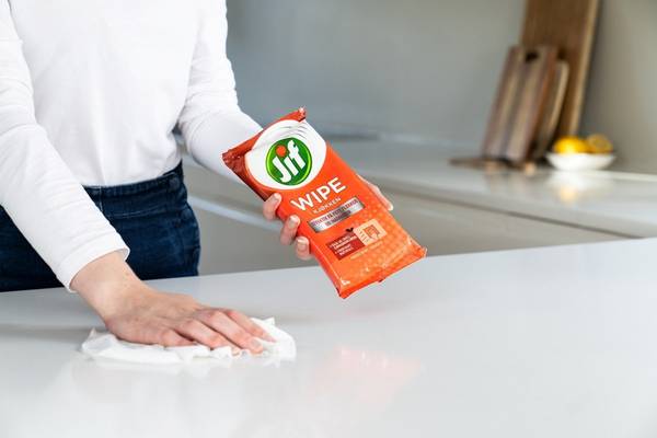 Person som tørker av kjøkkenbenken med Jif Wipes, med kjøkken i bakgrunnen.