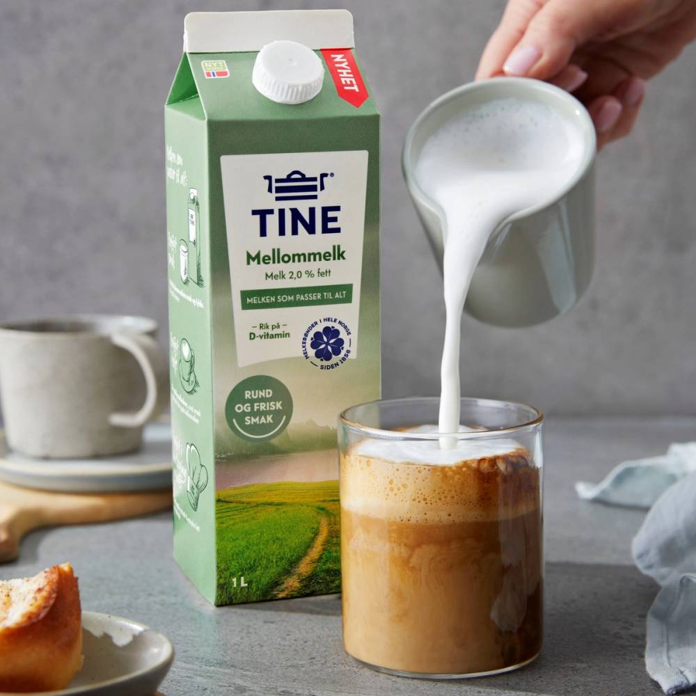 Kaffe med steamet melk som helles i et glass, med TINE Mellommelk pakke i bakgrunnen