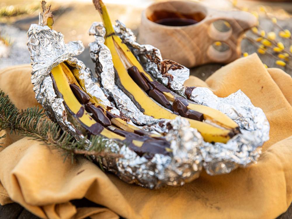 Banan med sjokolade og aluminiumsfolie på en turmatplate, klar til å spises ved bålet.