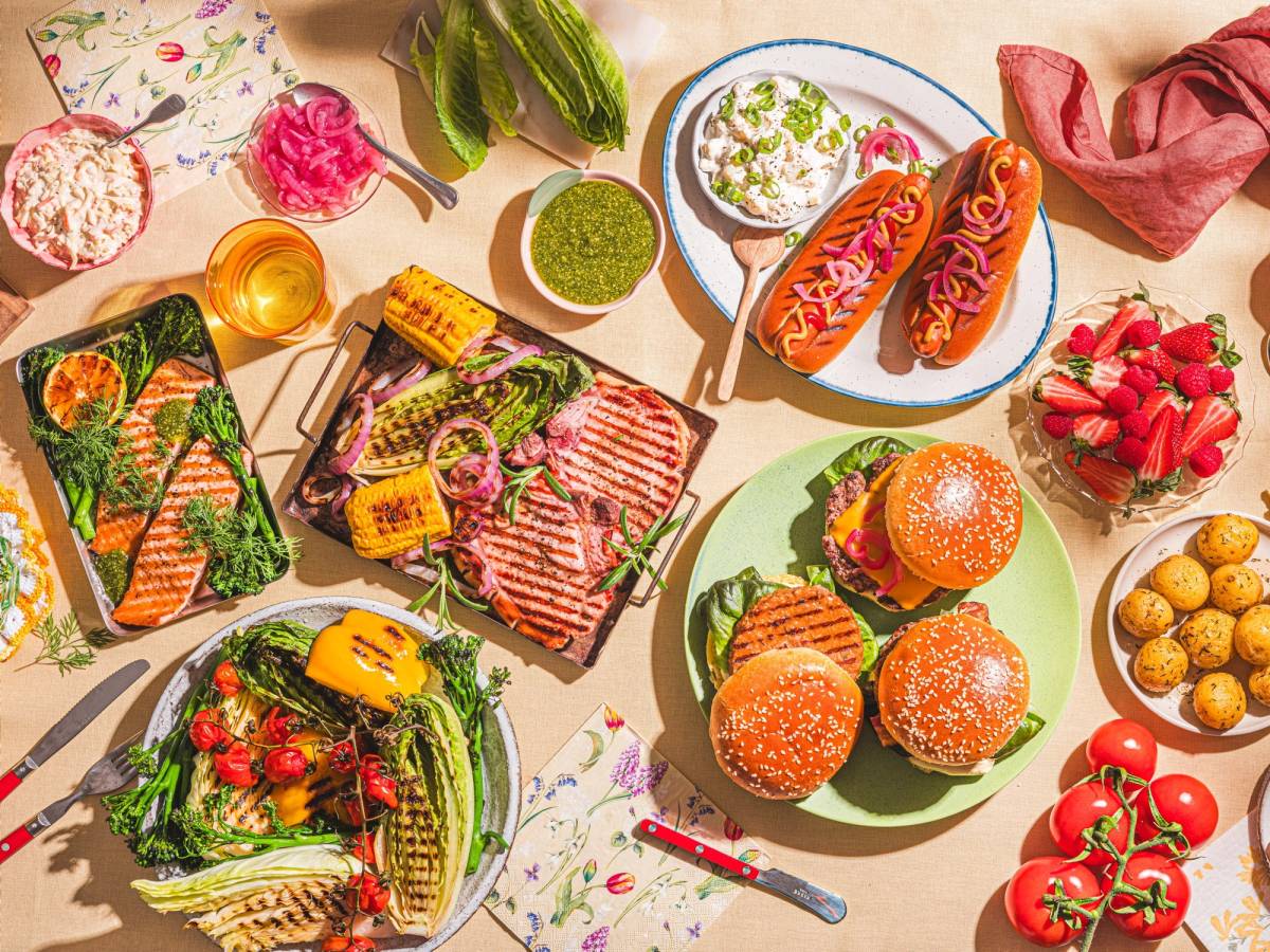 Et bord dekket med ulike kaker, frukt, grønnsaker og småretter til sommerfest.