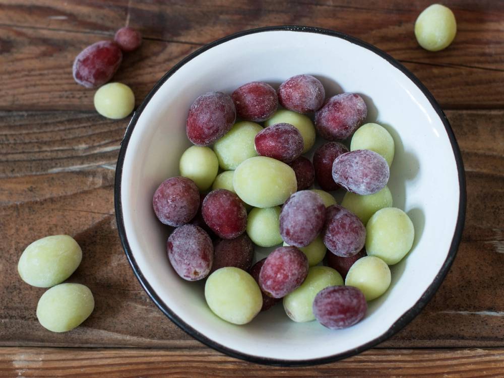 Frosne druer i en hvit bolle på et trebord