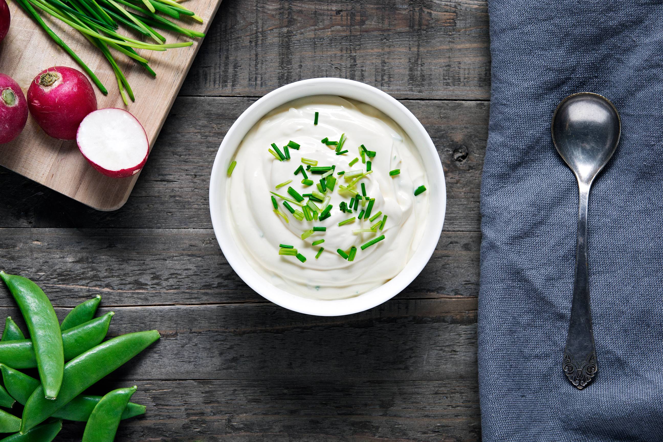 Rørosmeieriets økologiske rømme dip med hakket grønt på en hvit skål, omgitt av radiser og grønne blader på en treplate